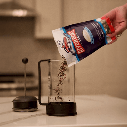 Person pouring tea Riverboat Tea into a french press on a kitchen counter.