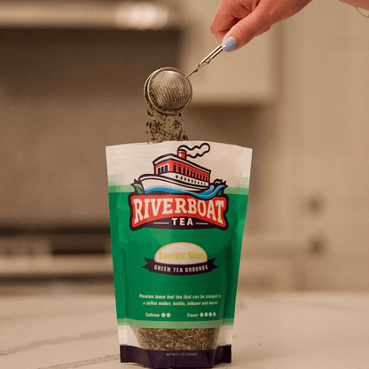 Person pouring tea from a bag labeled 'Riverboat Tea' into a infuser.